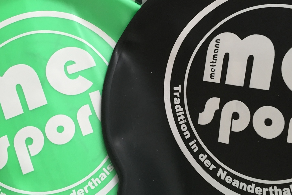 Schwimmkappen in Gr&uuml;n und Schwarz mit Hinweis auf 10 St&uuml;ck, verpackt in einer Box.