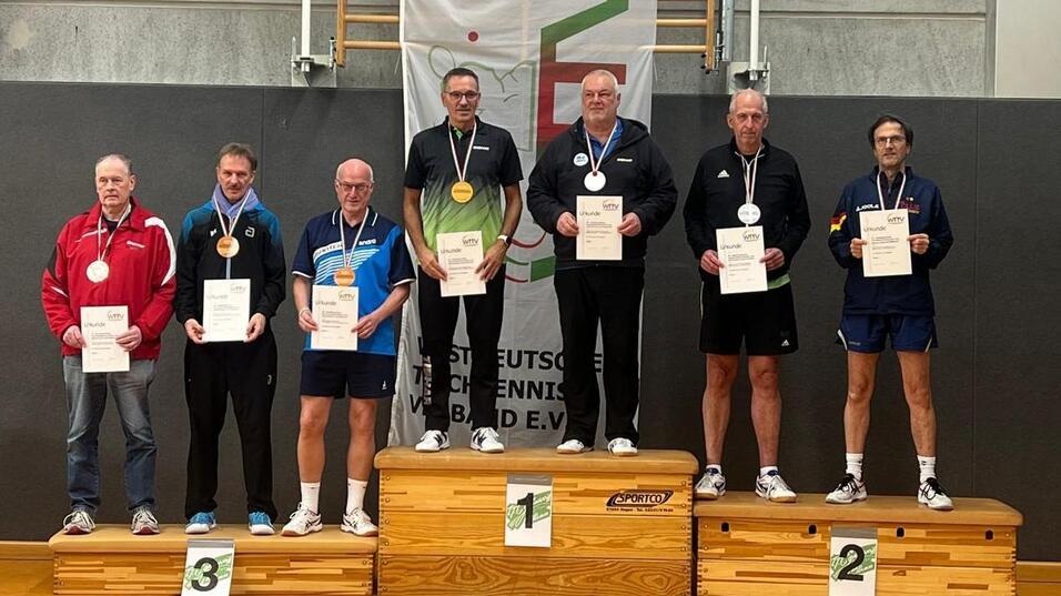 Sieben Tischtennisspieler stehen auf dem Siegertreppchen mit Medaillen und Urkunden.