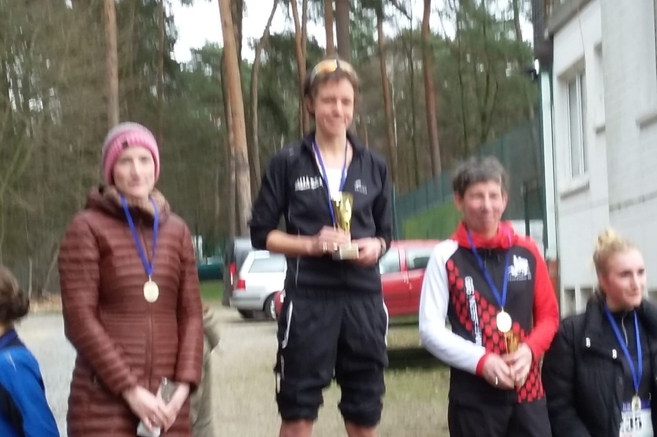 Vier Teilnehmerinnen stehen auf dem Siegerehrungs-Podest, eine hält einen Pokal, alle mit Medaillen um den Hals.