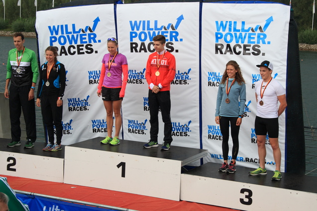 Sechs Sportler stehen auf dem Siegertreppchen mit Medaillen, umgeben von Werbung für "WILLPOWER RACES".