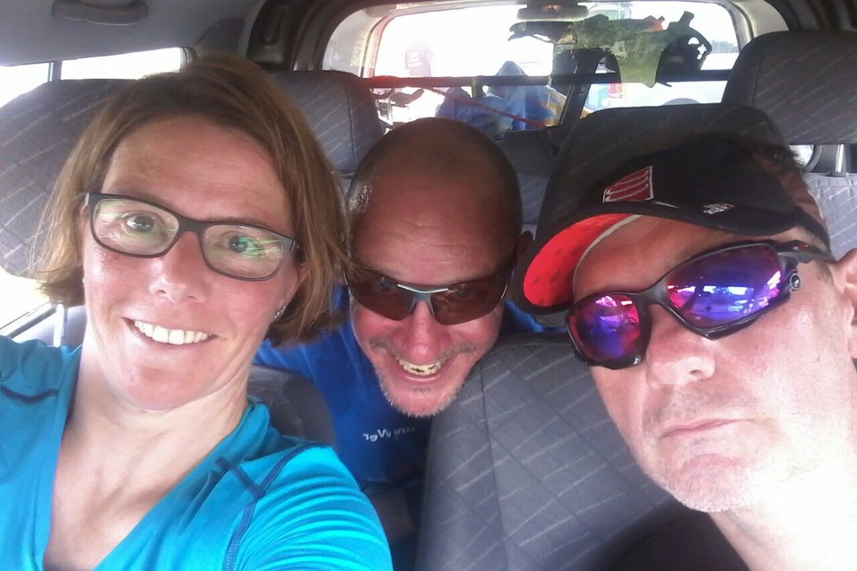 Drei Personen mit Sonnenbrillen sitzen in einem Auto und lächeln in die Kamera.