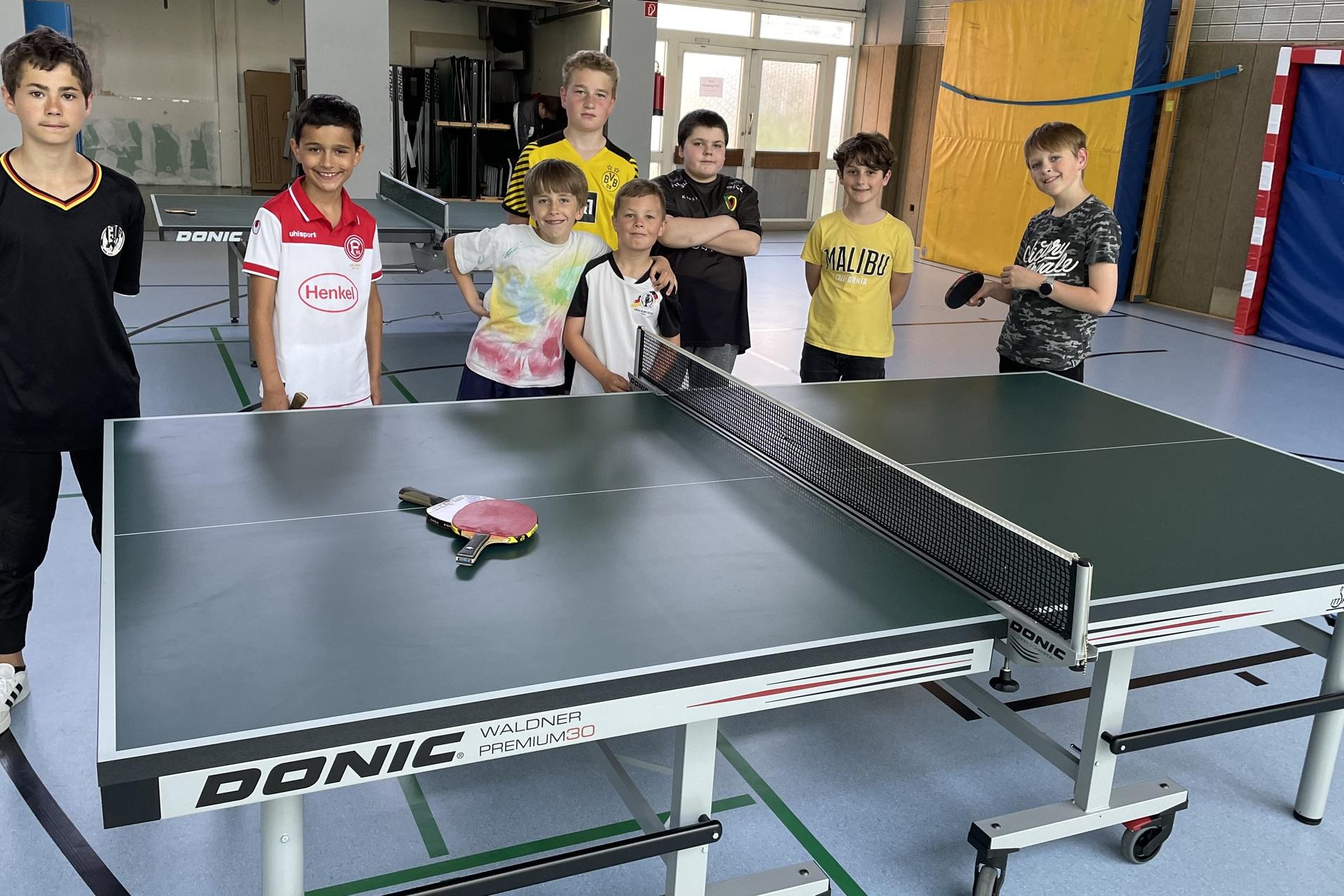 8 Jugendliche stehen um eine neue Tischtennisplatte herum und freuen sich darüber.