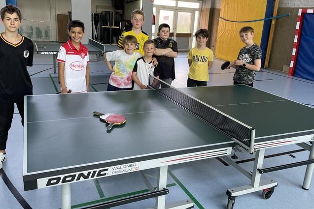 8 Jugendliche stehen um eine neue Tischtennisplatte herum und freuen sich darüber.