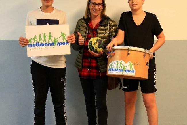 Steffi aus dem Vorstand des Fördervereins übergibt die neue Trommel zwei Jugendlichen aus der Handball Abteilung.