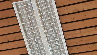 Lampeneinheit an einer Holzdecke mit horizontalen Laminierungen aus braunem Holz.