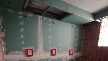 Raum mit grünem Trockenbau, drei roten Schaltern an der Wand und zwei runden Bodenausschnitten auf dem dunklen Boden.