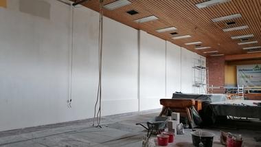 Blick in einen unfertigen Raum mit weißen Wänden, Baustellenmaterial und Werkzeugen auf dem Boden.