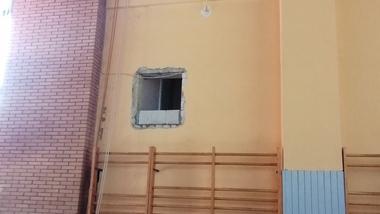 Innenansicht eines Raumes mit einem offenen Fenster, Holzbalken, Turnringen und einer Holzleiter an der Wand.