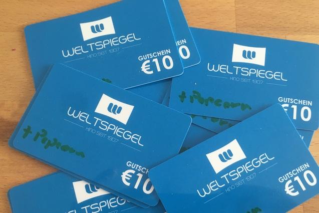 Stapel blauer Gutscheinkarten des Kinos &bdquo;Weltspiegel&ldquo; mit Werten von 10 Euro, einige mit handschriftlicher Notiz &bdquo;+Popcorn&ldquo;.