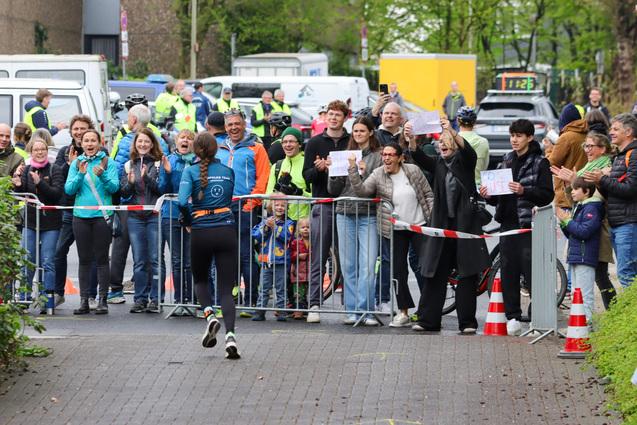 Läuferin im Wettkampf wird von jubelndem Publikum an der Strecke begeistert angefeuert.