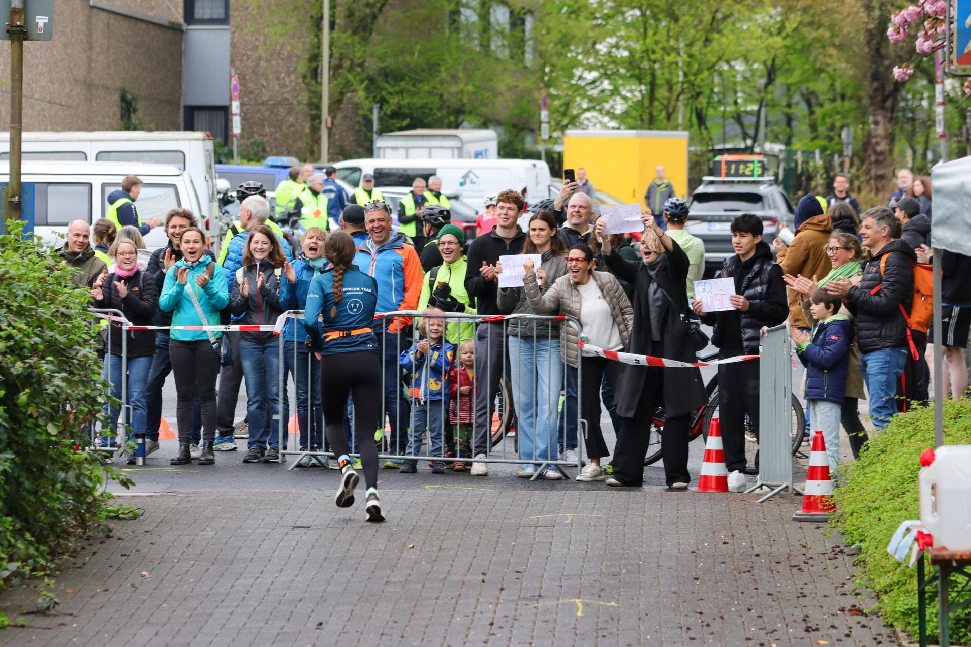 Läuferin im Wettkampf wird von jubelndem Publikum an der Strecke begeistert angefeuert.