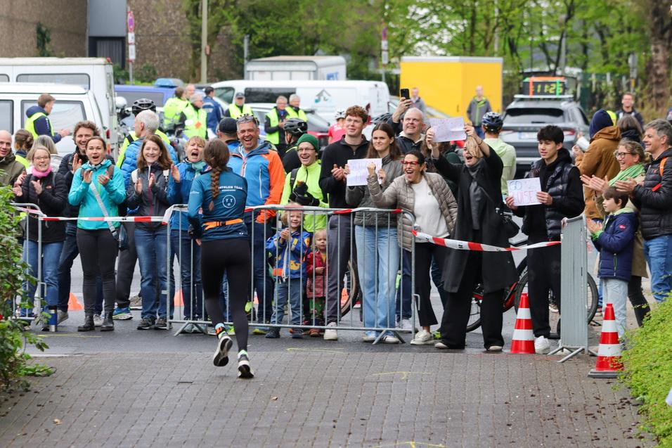 Läuferin im Wettkampf wird von jubelndem Publikum an der Strecke begeistert angefeuert.