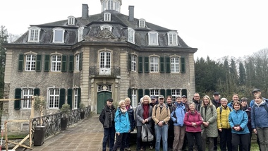 Gruppe von 20 Personen steht vor einem historischen Gebäude mit grünem Eingang und Fensterläden.