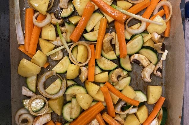 Blech mit gewürfeltem Gemüse: Zucchini, Karotten, Kartoffeln, Zwiebeln und Champignons auf Backpapier.