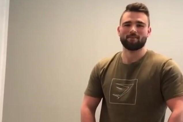 Junger Mann kniet auf Fitnessmatte, zwei Toilettenpapierrollen vor ihm auf dem Boden.