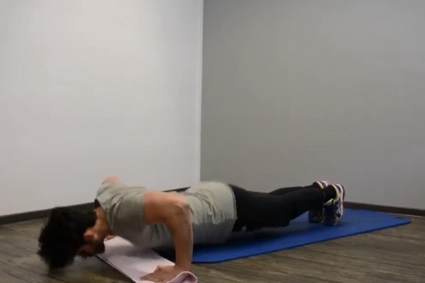 Mann macht Liegest&uuml;tze auf einer blauen Gymnastikmatte in einem hellen Raum mit Holzboden.