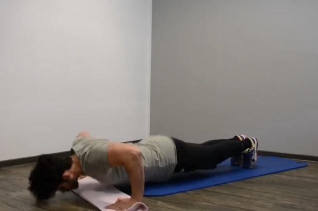 Mann macht Liegest&uuml;tze auf einer blauen Gymnastikmatte in einem hellen Raum mit Holzboden.