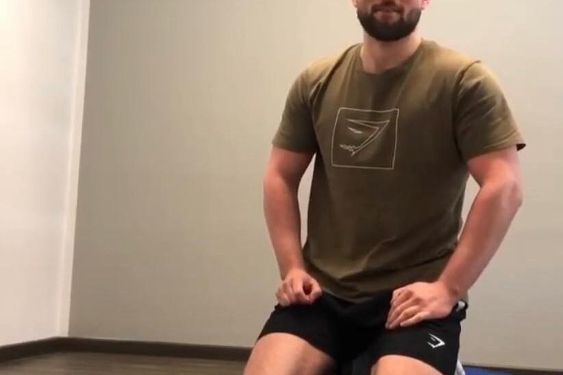 Junger Mann kniet auf Fitnessmatte, zwei Toilettenpapierrollen vor ihm auf dem Boden.