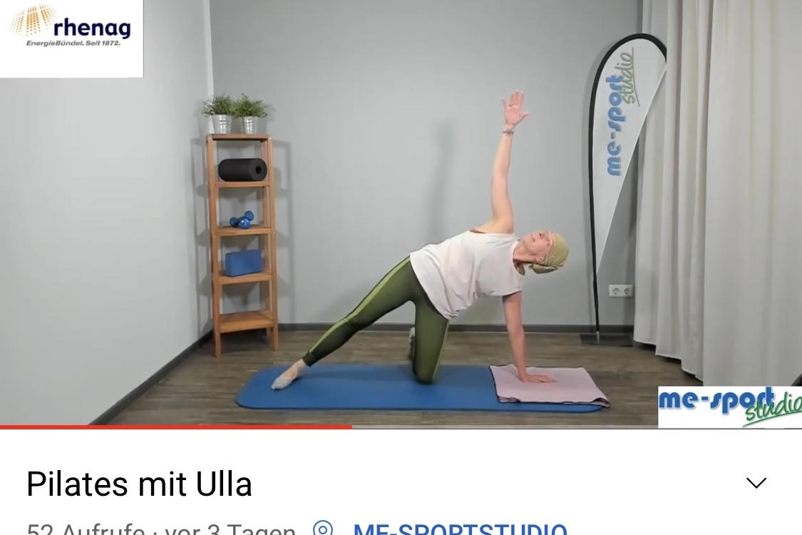 Frau in Pilates-Übung seitlich auf einer Matte, mit einem Arm nach oben gestreckt, Hintergrund mit Regalen.