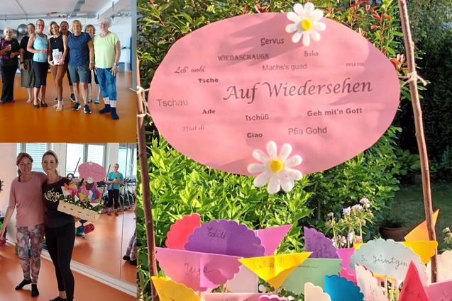 Gruppenfoto von Teilnehmern einer Veranstaltung mit einer dekorativen „Auf Wiedersehen“-Tafel und bunten Fähnchen auf Tisch.