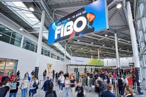 Menschenmenge vor einem großen FIBO-Werbeschild in einem modernen Messegebäude.